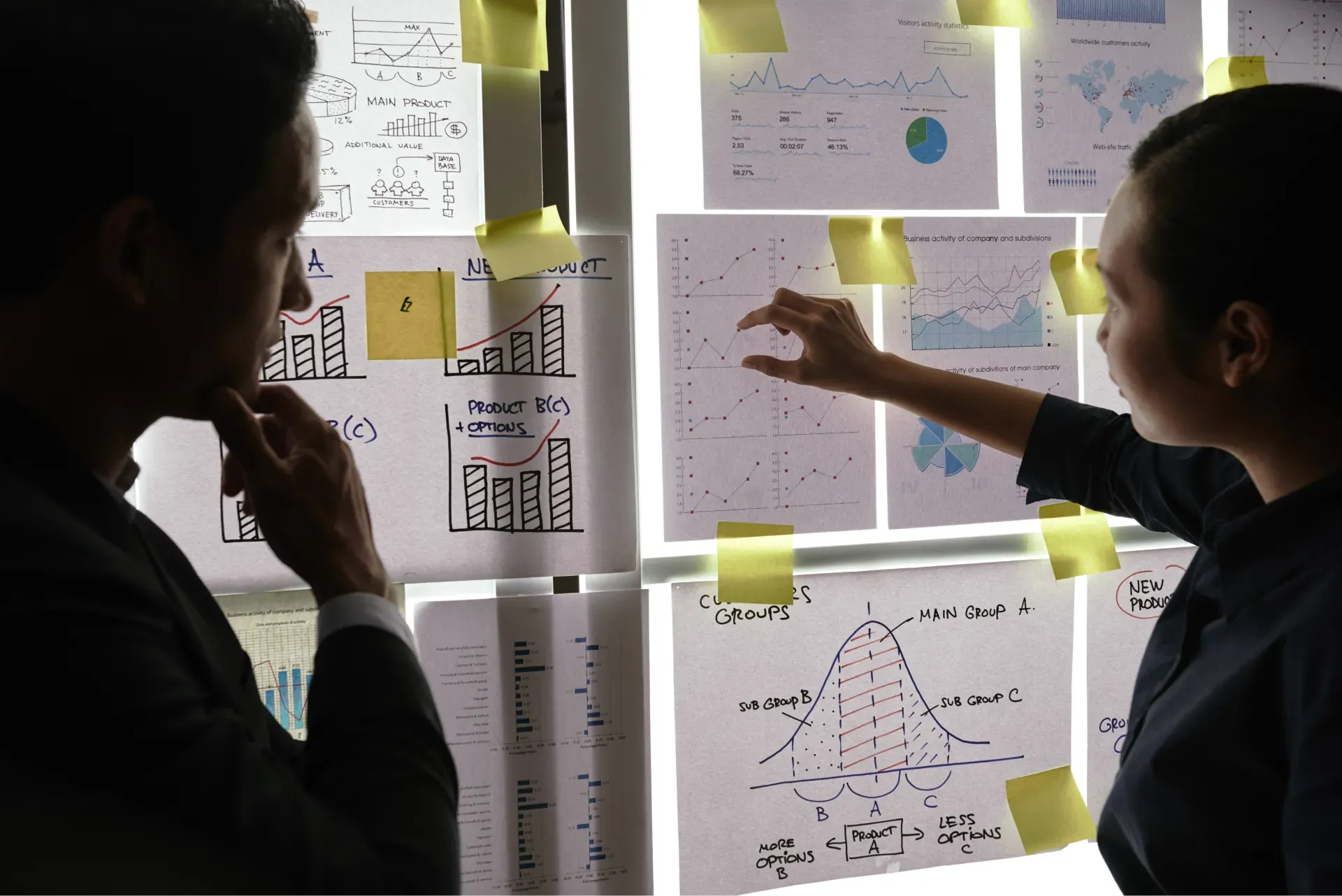 male_female_colleagues_standing_by_window_looking_business_graphs_it_1.webp